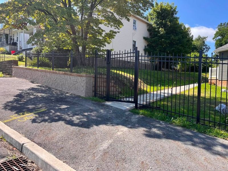 Black metal fence and gate with stucco retaining wall