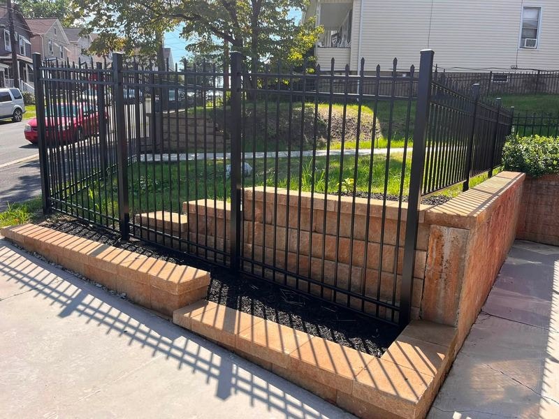 Block retaining wall with black metal fence
